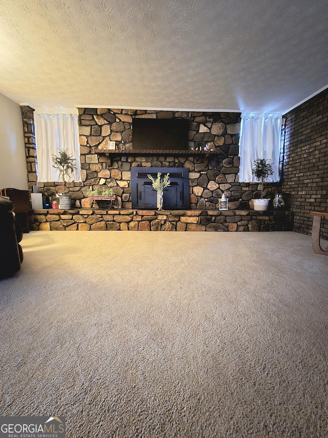 unfurnished living room featuring carpet floors, a healthy amount of sunlight, a fireplace, and a textured ceiling