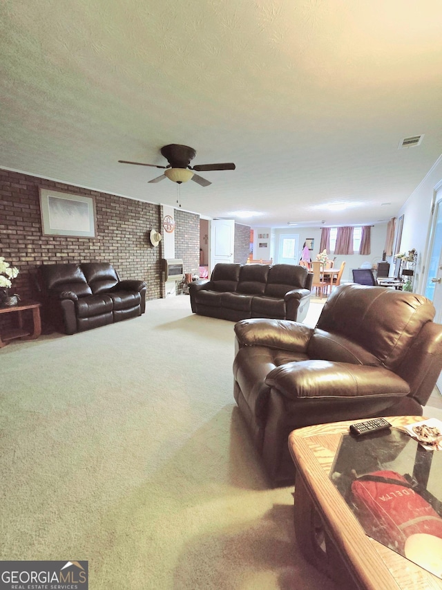 living room featuring ceiling fan, brick wall, a textured ceiling, and carpet