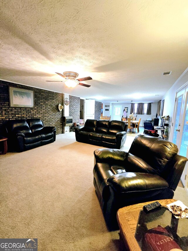 living room featuring ceiling fan, carpet floors, a textured ceiling, and brick wall