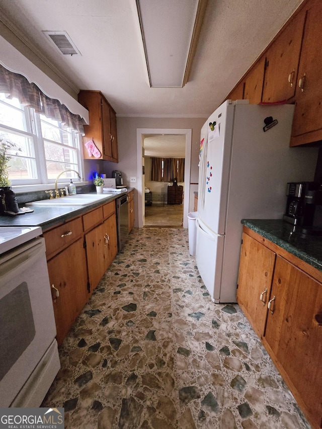 kitchen featuring white appliances, visible vents, brown cabinetry, stone finish floor, and a sink