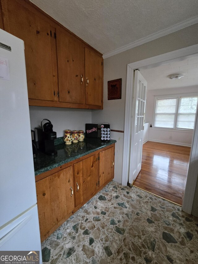 kitchen featuring white refrigerator, crown molding, and a textured ceiling