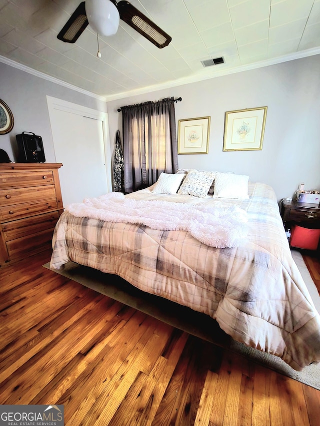 bedroom featuring ornamental molding, wood finished floors, visible vents, and a ceiling fan