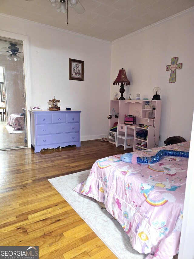 bedroom with ornamental molding and wood finished floors