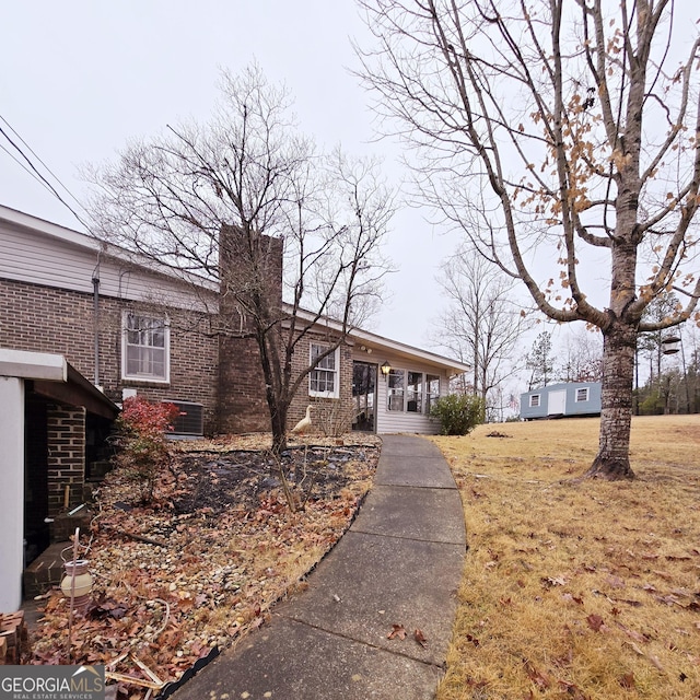 view of property exterior featuring brick siding, a yard, and a chimney