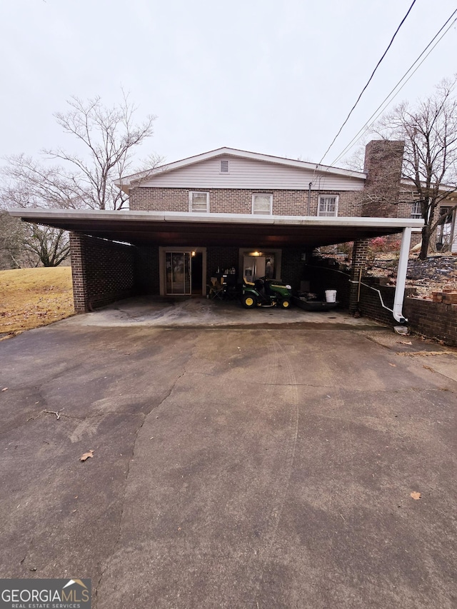 exterior space featuring a carport, aphalt driveway, and brick siding