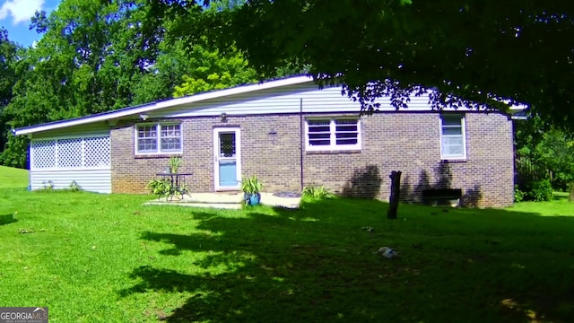 rear view of property with brick siding and a lawn