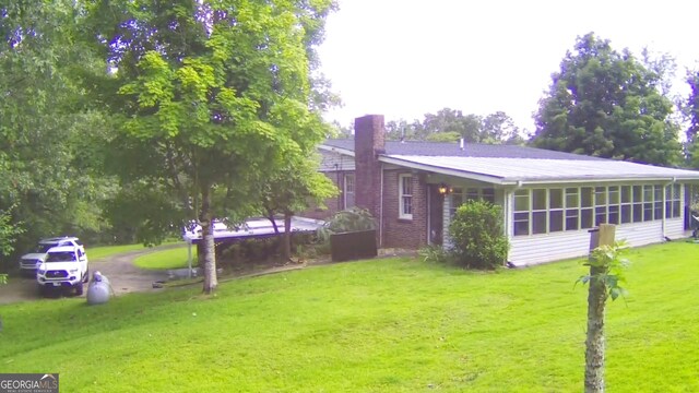 rear view of property with a yard, a chimney, and a sunroom