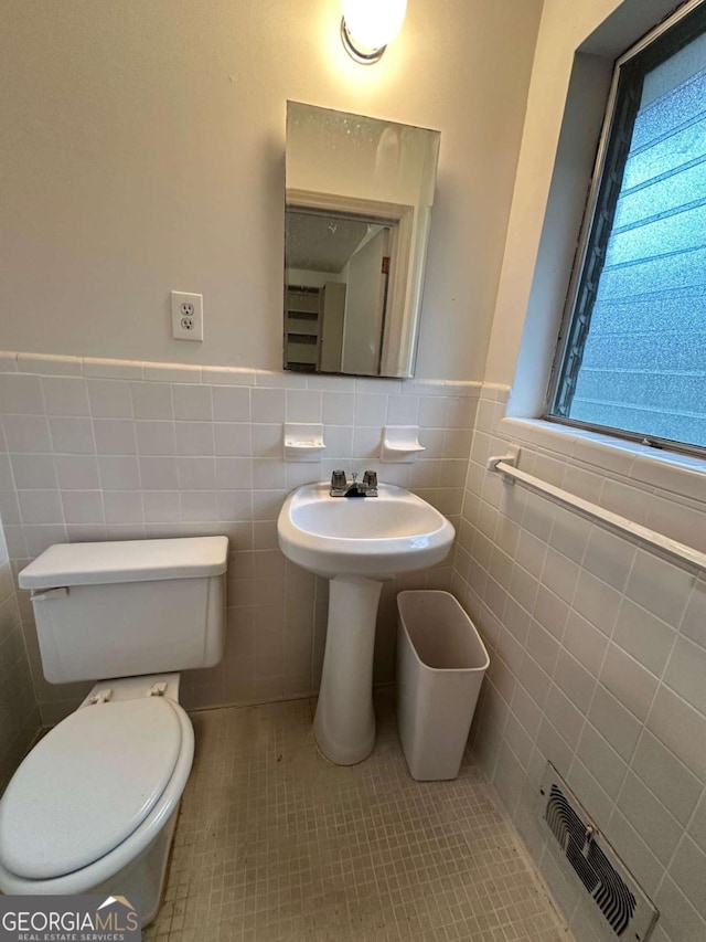 bathroom featuring tile patterned flooring, tile walls, and toilet