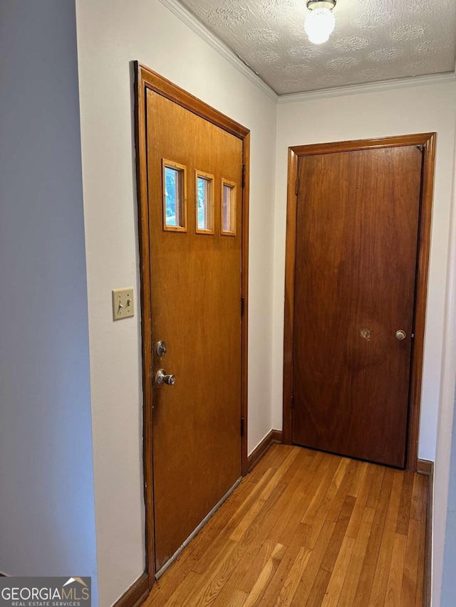 entryway featuring ornamental molding, a textured ceiling, and light hardwood / wood-style floors