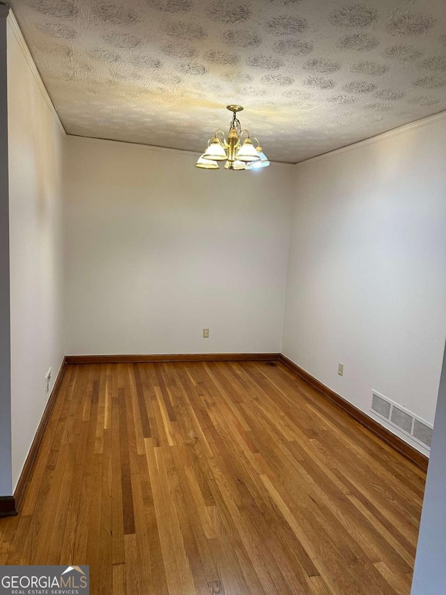 unfurnished room featuring hardwood / wood-style flooring, a chandelier, and a textured ceiling