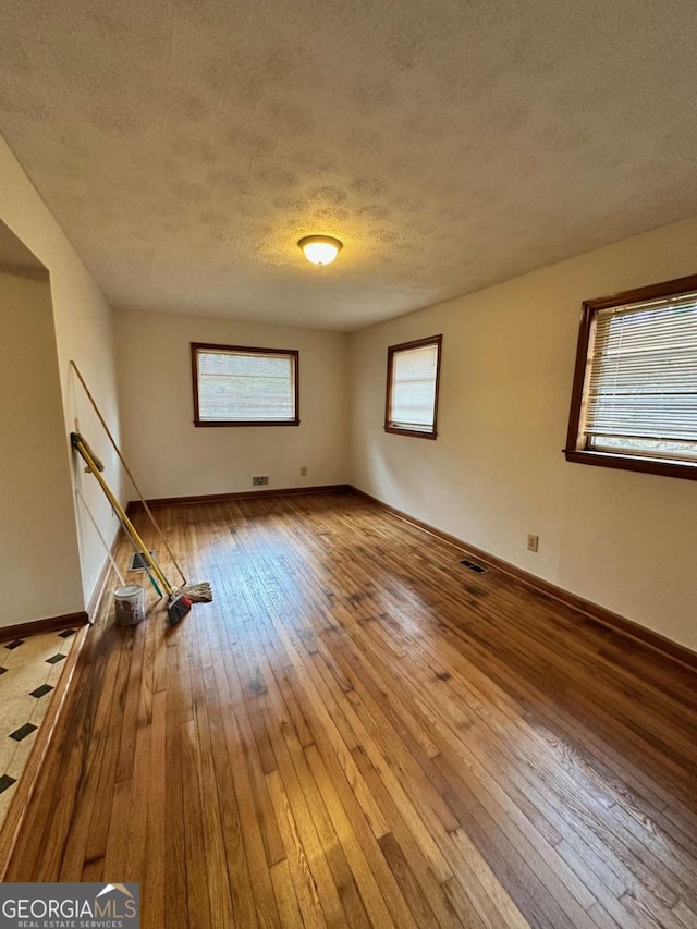 empty room featuring hardwood / wood-style flooring and a textured ceiling