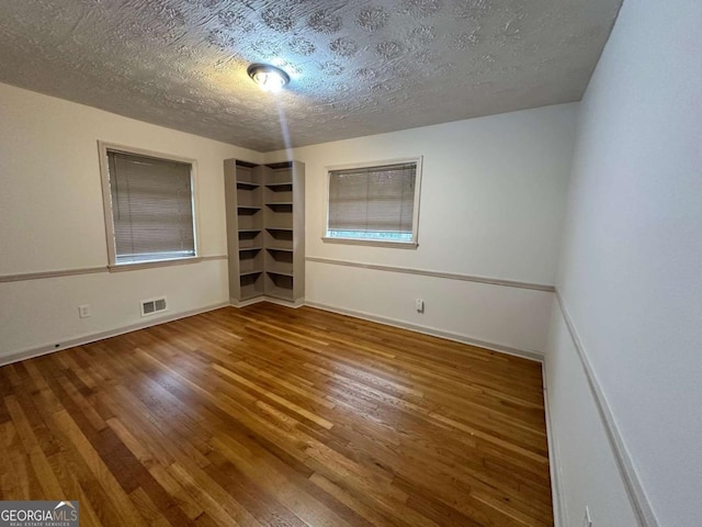 spare room featuring hardwood / wood-style floors and a textured ceiling