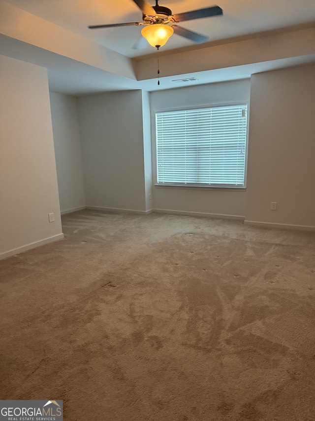 carpeted empty room featuring ceiling fan and a tray ceiling