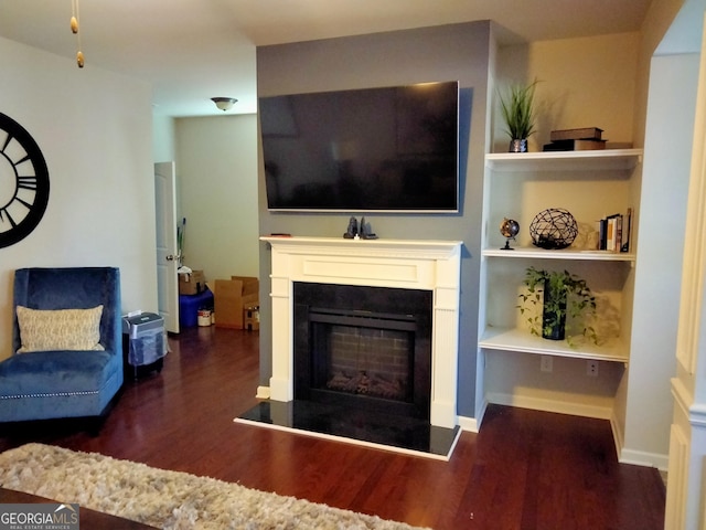 living room with dark hardwood / wood-style flooring and built in shelves