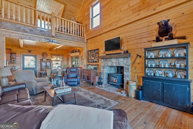 living room with a towering ceiling, a wealth of natural light, hardwood / wood-style floors, and wood walls