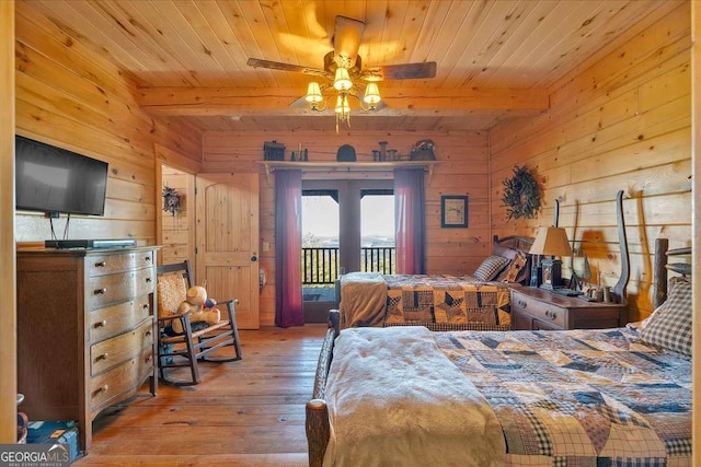 bedroom with light hardwood / wood-style flooring, beam ceiling, and wooden walls