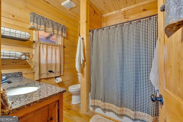 bathroom with vanity, wood-type flooring, wooden walls, and toilet