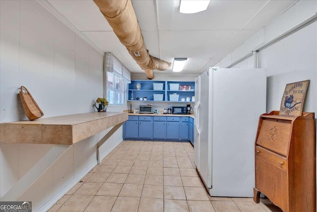 kitchen with blue cabinetry and white refrigerator