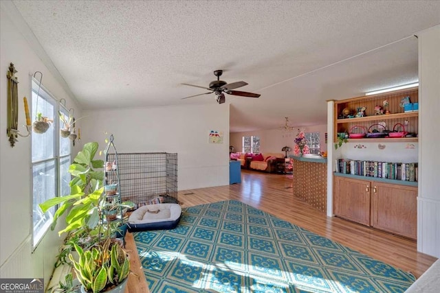 living area featuring hardwood / wood-style flooring, ceiling fan, and a textured ceiling