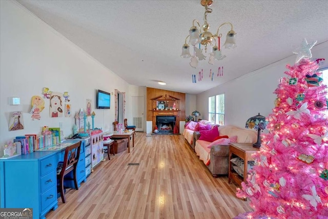 living room featuring vaulted ceiling, a textured ceiling, wooden walls, a notable chandelier, and light hardwood / wood-style floors