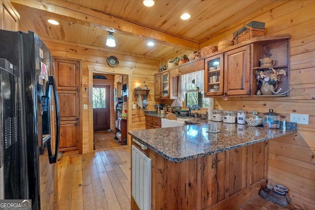 kitchen featuring black fridge, wood walls, kitchen peninsula, and beamed ceiling