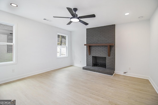 unfurnished living room featuring a brick fireplace, ceiling fan, and light hardwood / wood-style flooring