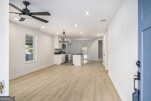 unfurnished living room featuring ceiling fan, sink, and light hardwood / wood-style floors