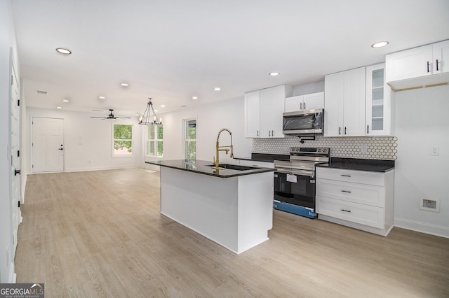 kitchen with appliances with stainless steel finishes, sink, white cabinets, and light hardwood / wood-style flooring