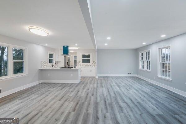 unfurnished living room featuring sink, light hardwood / wood-style flooring, and a wealth of natural light