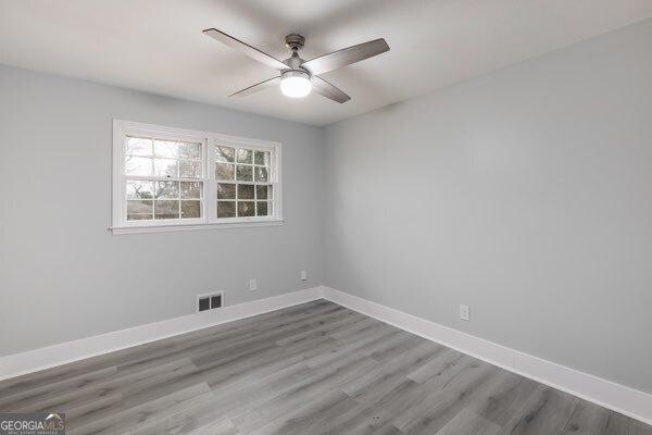 spare room featuring wood-type flooring and ceiling fan