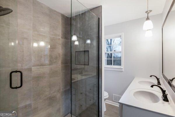 bathroom featuring vanity, a shower with door, and toilet