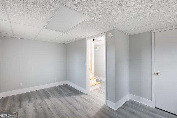 basement with a paneled ceiling and light hardwood / wood-style floors