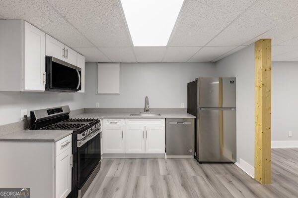 kitchen with white cabinetry, appliances with stainless steel finishes, sink, and a paneled ceiling