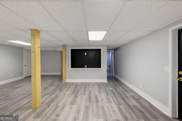 basement with a drop ceiling and light hardwood / wood-style floors