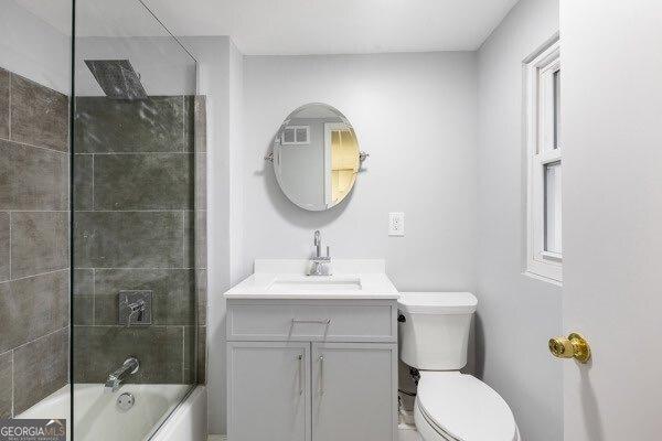 full bathroom with tiled shower / bath, vanity, and toilet