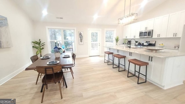 kitchen featuring pendant lighting, tasteful backsplash, white cabinetry, lofted ceiling, and range