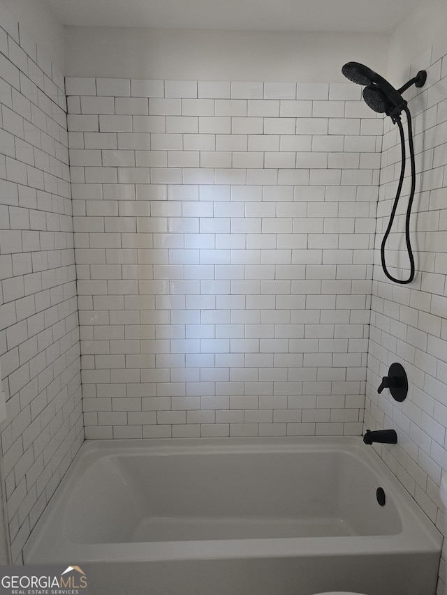 bathroom featuring toilet and tiled shower / bath