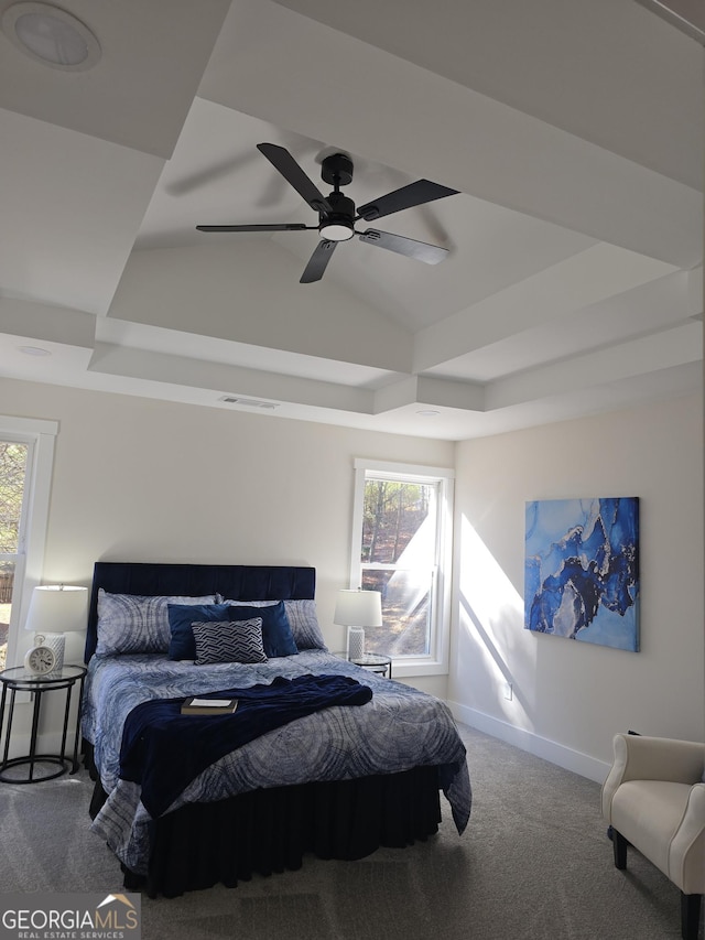 bedroom featuring ceiling fan, a raised ceiling, carpet floors, and multiple windows