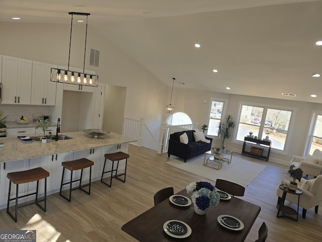 interior space featuring sink, light hardwood / wood-style flooring, and high vaulted ceiling