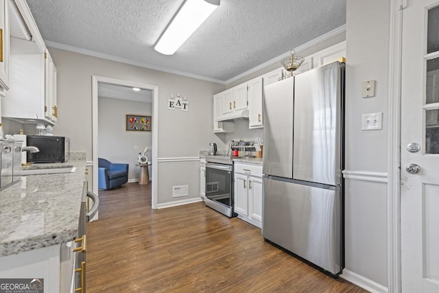 kitchen with light stone counters, a textured ceiling, ornamental molding, appliances with stainless steel finishes, and white cabinets