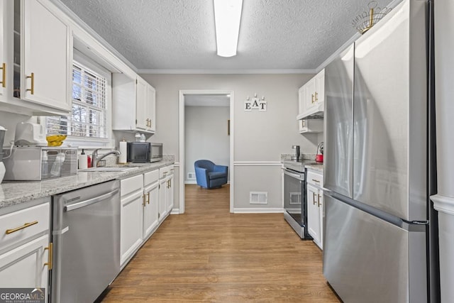 kitchen featuring sink, stainless steel appliances, light stone countertops, a textured ceiling, and white cabinets