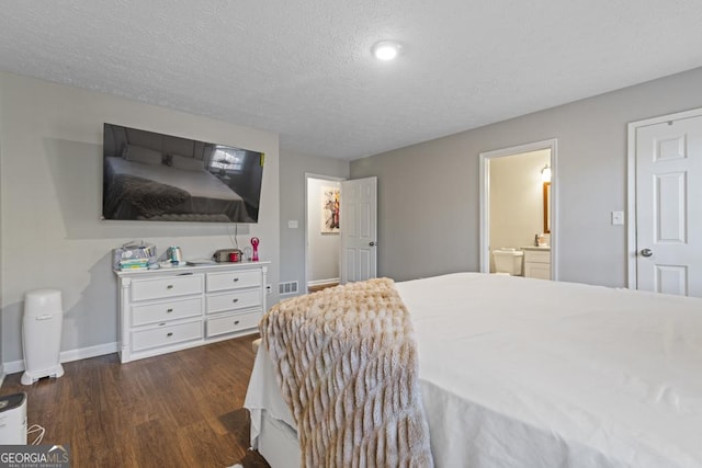 bedroom with connected bathroom, a textured ceiling, and dark hardwood / wood-style flooring