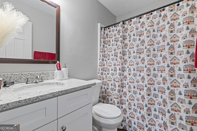 bathroom with vanity, toilet, and a textured ceiling