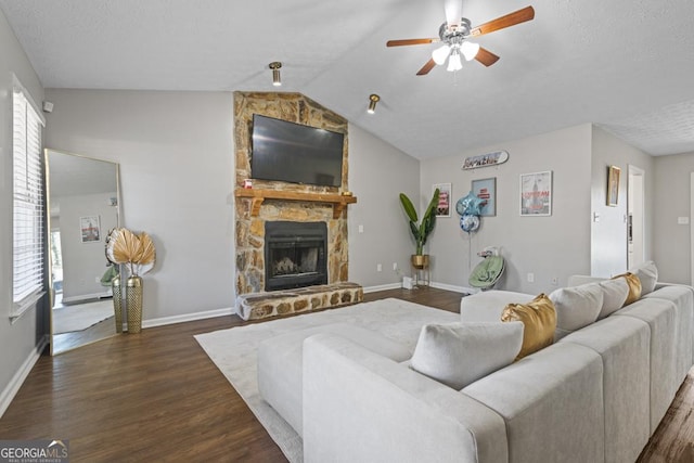 living room with a fireplace, dark hardwood / wood-style floors, ceiling fan, and vaulted ceiling