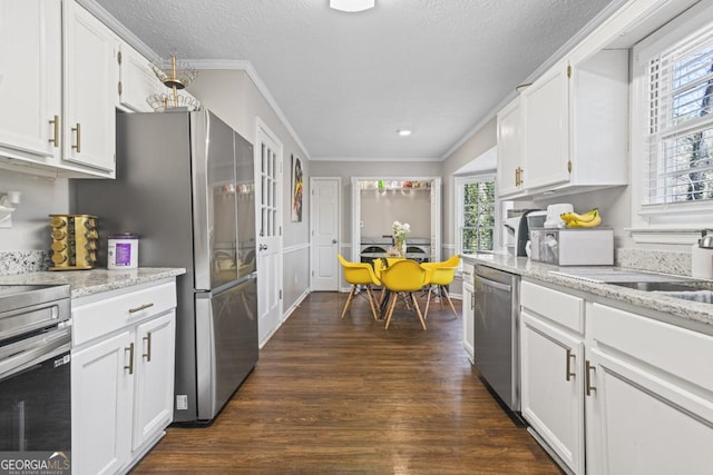 kitchen featuring crown molding, appliances with stainless steel finishes, white cabinetry, light stone countertops, and dark hardwood / wood-style flooring