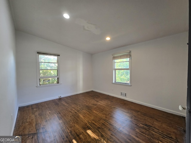 spare room with dark wood-type flooring and vaulted ceiling