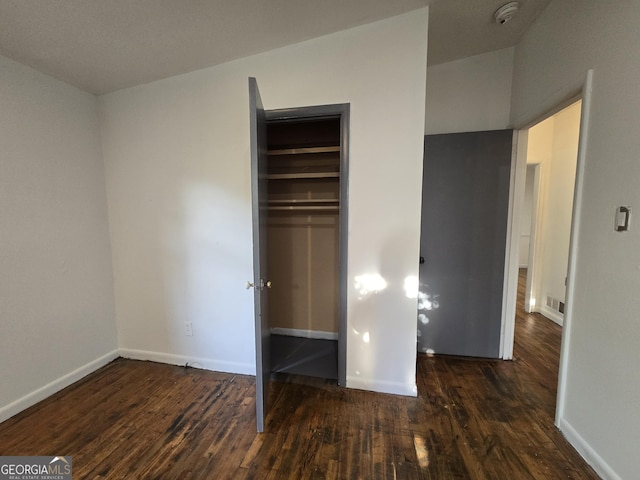 unfurnished bedroom featuring dark hardwood / wood-style flooring and a closet