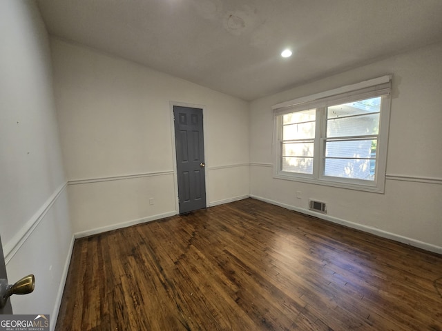 empty room featuring lofted ceiling and dark hardwood / wood-style flooring