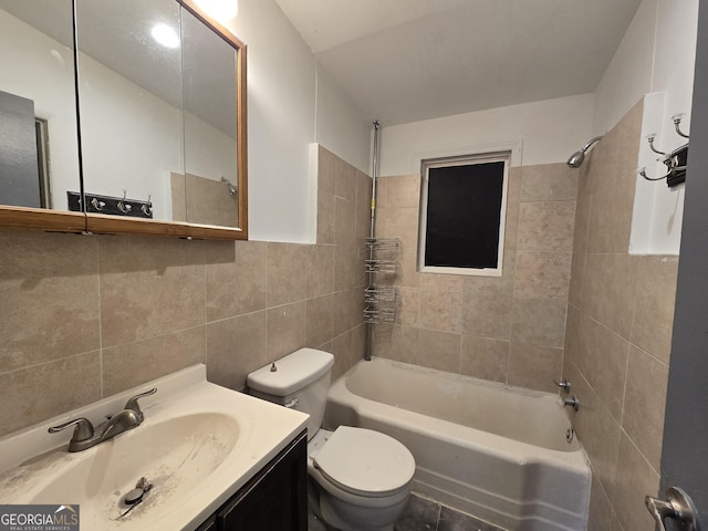 full bathroom featuring vanity, toilet, tile walls, and tiled shower / bath