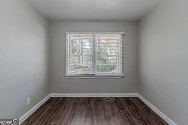 empty room with dark hardwood / wood-style floors and a wealth of natural light